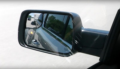 A yellow triangle flashes in the mirror to alert the driver of a vehicle that’s entering the blindspot of the 2019 Ram 1500.