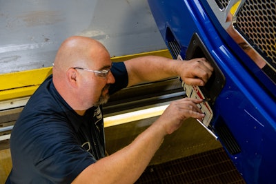 A technician adjusts an ADAS sensor on the front of a truck.